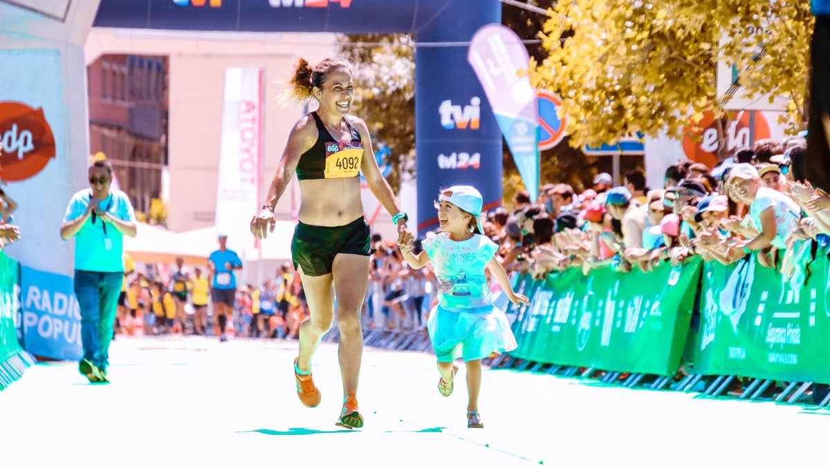 A joyful mother and daughter cross the marathon finish line hand in hand, exuding happiness and energy.
